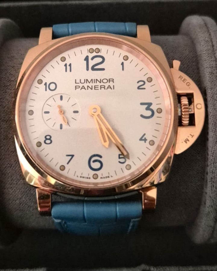 Panerai Luminor in a rose gold case with a white dial and blue strap in a watch box